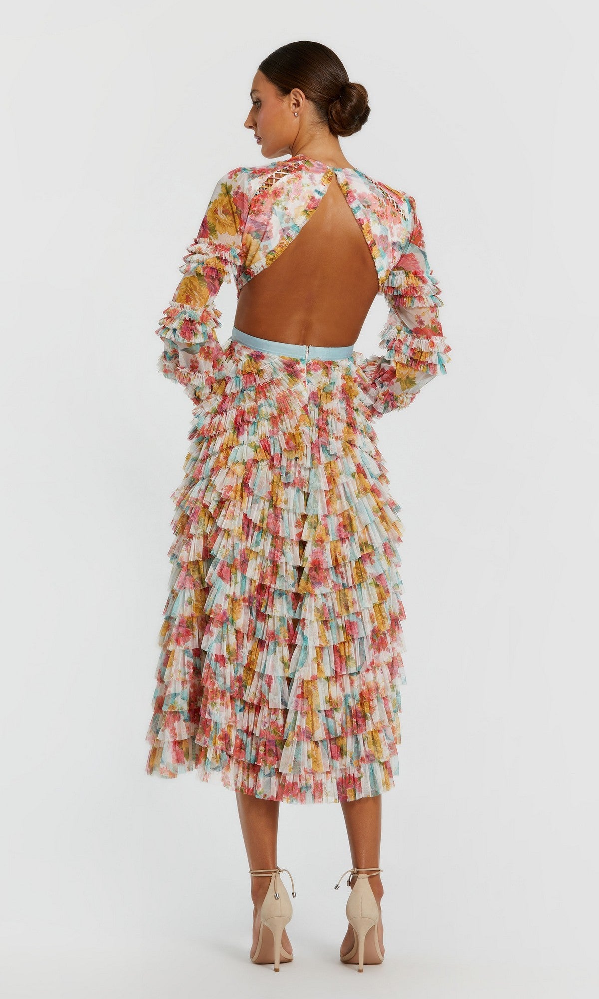 A woman stands in heels, wearing the Mac Duggal 8130 Midi Wedding Guest Dress—a long-sleeve, mid-length dress with a multicolored floral print and open back—facing away against a plain white background.